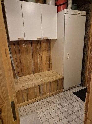A small room with a wooden bench, a white cabinet, and a white refrigerator. - Kieruka C | Cozy Log Cabin | Sauna & Fireplace (Ruka)