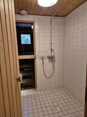 Un piccolo bagno con rivestimento piastrellato, una porta in legno e uno schermo televisivo visibile.