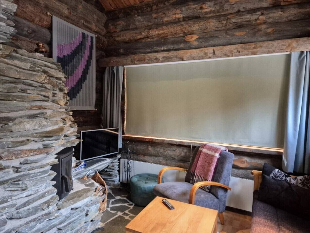 A cozy room with a stone fireplace, a television, a wooden table, and a comfortable seating area.
