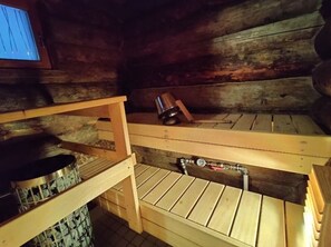 A wooden cabin interior with bunk beds, a stove, and a water spigot.