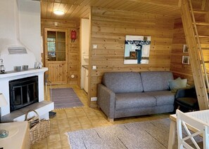 A cozy cabin interior with a fireplace, sofa, and wooden walls. - Mestarikämpät B 9 | Cozy Lakeside Cottage & Sauna (Ruka)