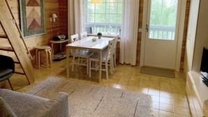 Huoneen sisustus on tehty puusta, ja siellä on ruokapöytä, tuoleja, kello, lamppu ja televisio.