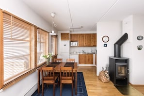 A compact kitchen with wooden cabinets, a microwave, and a black stove. - Karhunvartijan Kota | Ruka Center & Ski Pass (Ruka)