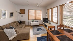 Ein Wohnzimmer mit Sofa, Fernseher und Essbereich mit Tisch und Stühlen.