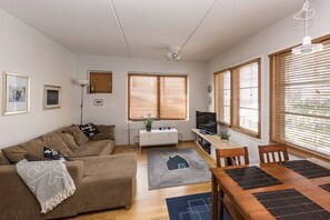 A living room with a sofa, TV, and dining area with a table and chairs. - Karhunvartijan Kota | Ruka Center & Ski Pass (Ruka)