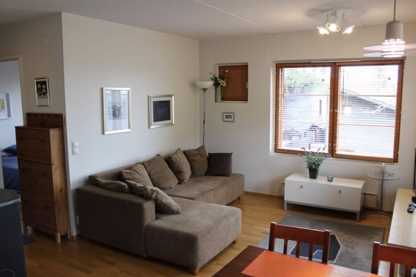 A living room with a sofa, a dining table, and a window with blinds.
