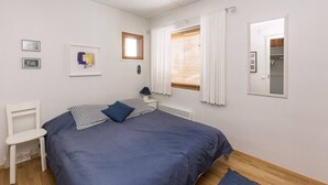 Ein Schlafzimmer mit Bett, einem Sessel, einem Fenster mit Vorhängen und einer Heizung.