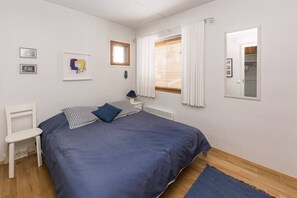 A bedroom with a bed, a chair, a window with curtains, and a radiator. - Karhunvartijan Kota | Ruka Center & Ski Pass (Ruka)