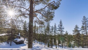 A snowy forest with a cabin and a wooden deck. - Jyrkkälä B | Family-Friendly Apt Near Ski Slopes (Ruka)