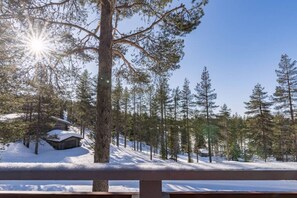 Ein verschneiter Wald mit einer Hütte und einer Holzterrasse.