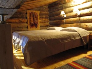 A log cabin bedroom with a bed, a wooden headboard, a wall-mounted lamp, and a rug on the floor. - Rukanpovi RP 7 | Cozy 1BR Cabin in Ruka (Ruka)