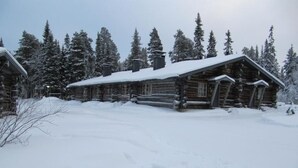 En hytte med et snedækket tag, omgivet af sneklædte træer.