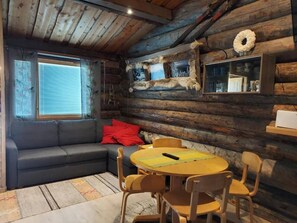 A log cabin interior with a sofa, round wooden table, and chairs.