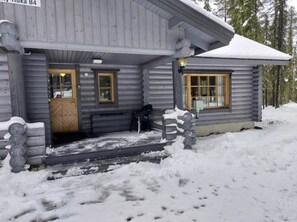 Eine Holzhütte mit Holztür und -fenstern, umgeben von Schnee.