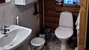 A compact bathroom with a sink, toilet, and a window with a curtain. - Mäntyruka B4 | Rustic Log Cabin for 6 in Ruka (Ruka)