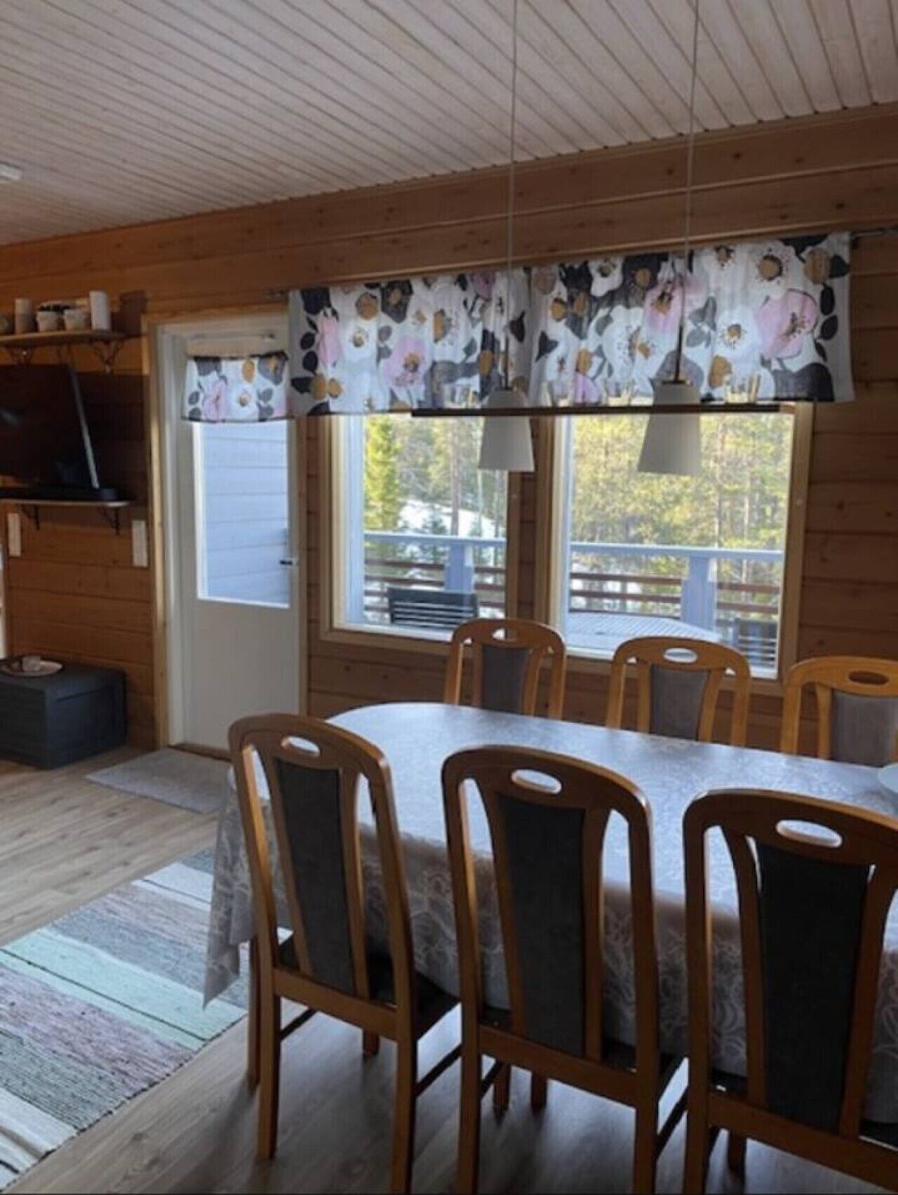 Dining area with a large wooden table and seating for six beside the window.
