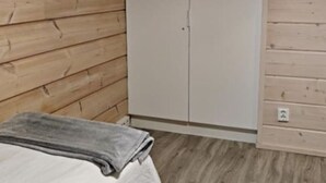 Huoneessa on sänky, vaatekaappi ja kattovalaisin.