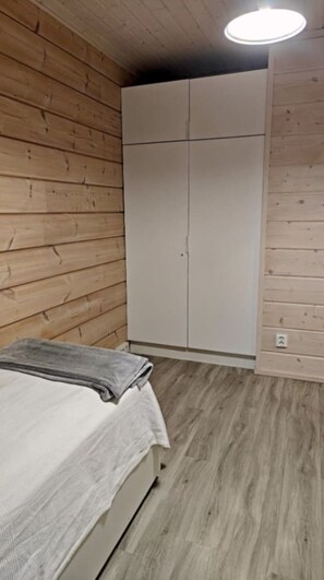 A room with a bed, a wardrobe, and a ceiling light. - Villa Viihy | Modern 2BR Villa Near Ski Slopes (Ruka)