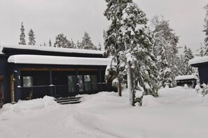 A snow-covered building with a covered porch and steps leading to the entrance.