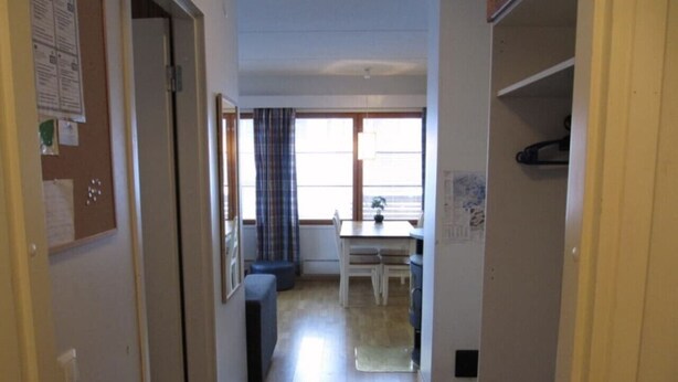 A narrow hallway leading to a dining area with a table and chairs, a window with curtains, and a door on the left. - Central 1BR Apt next to Ski Slopes | Ruka Centre (Ruka)