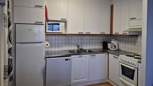 A compact kitchen with white cabinets, a microwave, a sink, a stove, and a dishwasher. - Central 1BR Apt next to Ski Slopes | Ruka Centre (Ruka)