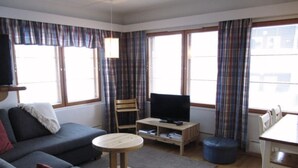 A living room with a sofa, a small round table, a television on a stand, and a dining table with chairs. - Central 1BR Apt next to Ski Slopes | Ruka Centre (Ruka)