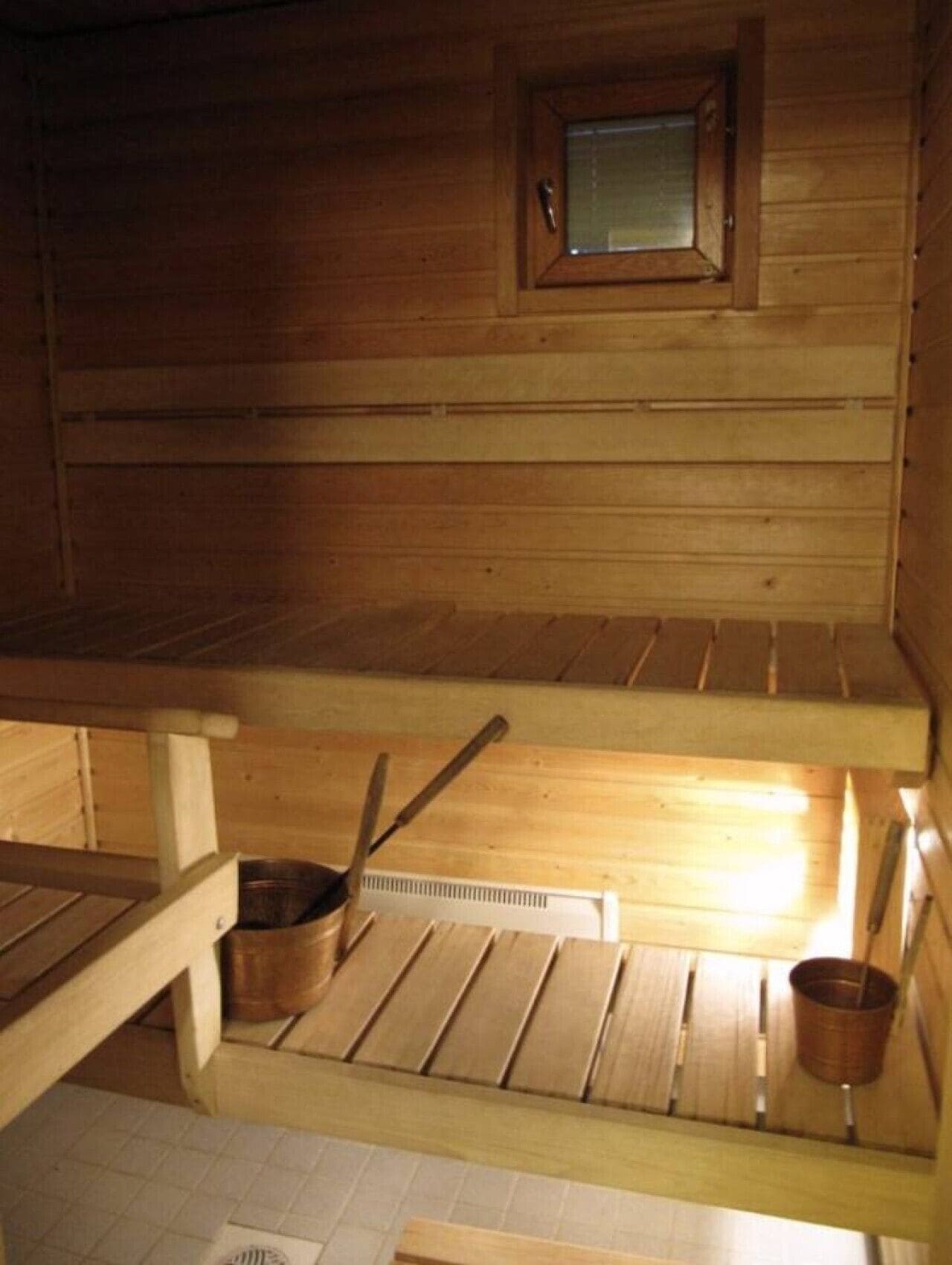 A wooden sauna with benches, a small window, and a sauna heater.