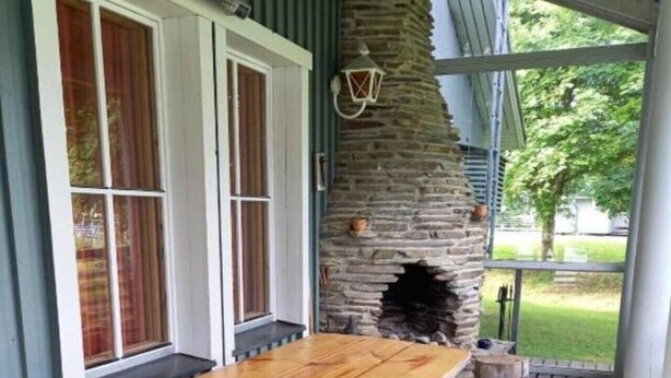 Una terraza de madera con una chimenea de piedra y una mesa con bancos.
