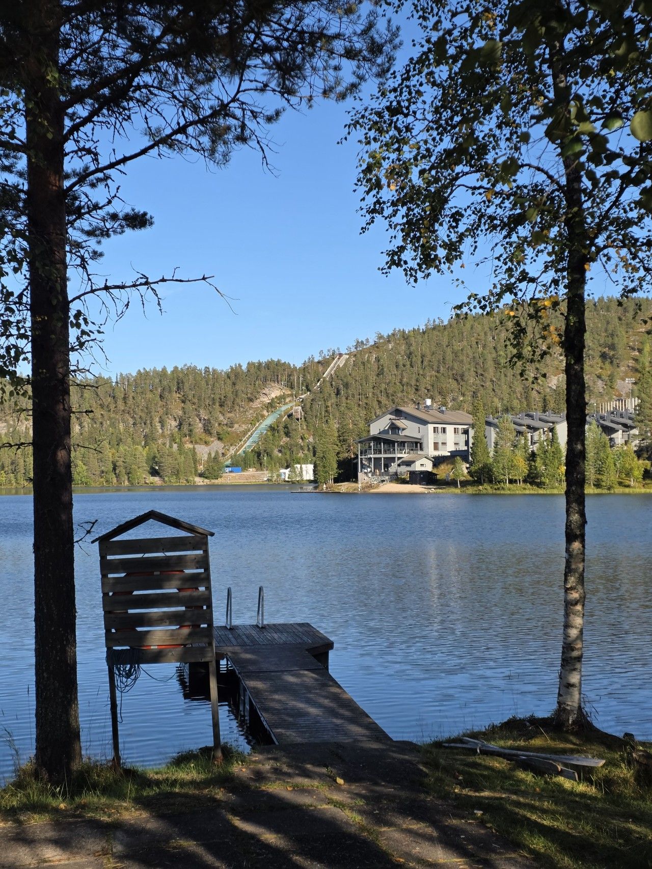 Una propietat al costat del llac amb un moll, una estructura de fusta i una casa al fons.