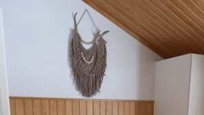 Un dormitorio con cabecera de madera, cama con colcha estampado de estrellas y un colgador de macramé en la pared.