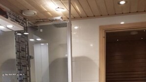 Un baño con cabina de ducha de vidrio, un lavabo y un banco de madera.