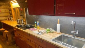 Een keuken met een houten aanrecht, een roestvrijstalen spoelbak en rode kastjes.