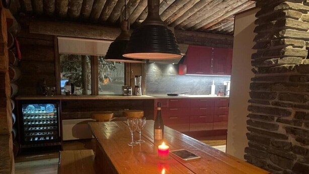 Een houten bar met een kaars, glazen en een fles.