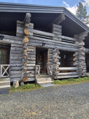 Eine Blockhütte mit Veranda, Holzstufen und einem Fenster.