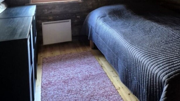 Una habitación pequeña y acogedora con una cama individual, un aparador y una ventana que deja entrar luz natural.