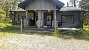 A log cabin with a porch, a chimney, and a gravel driveway. - Mäntyruka A1 | Cozy 1BR Cabin with Loft & Sauna (Ruka)