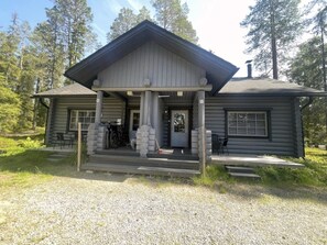 Eine Blockhütte mit Veranda, Schornstein und einem Schotterweg.