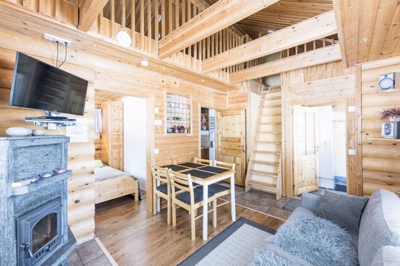 Interior de una cabaña de madera con comedor, chimenea y televisor.