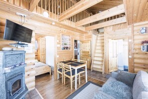 Ein Holzhütten-Innenraum mit Essbereich, Kamin und Fernseher.