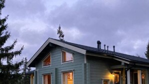A two-story house with a porch, large windows, and a chimney. - Nietos A | Comfy Cabin in Ruka | Private Sauna (Ruka)