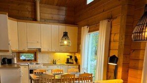 A modern log cabin interior with a sectional sofa, dining table, and kitchen area. - Nietos A | Comfy Cabin in Ruka | Private Sauna (Ruka)