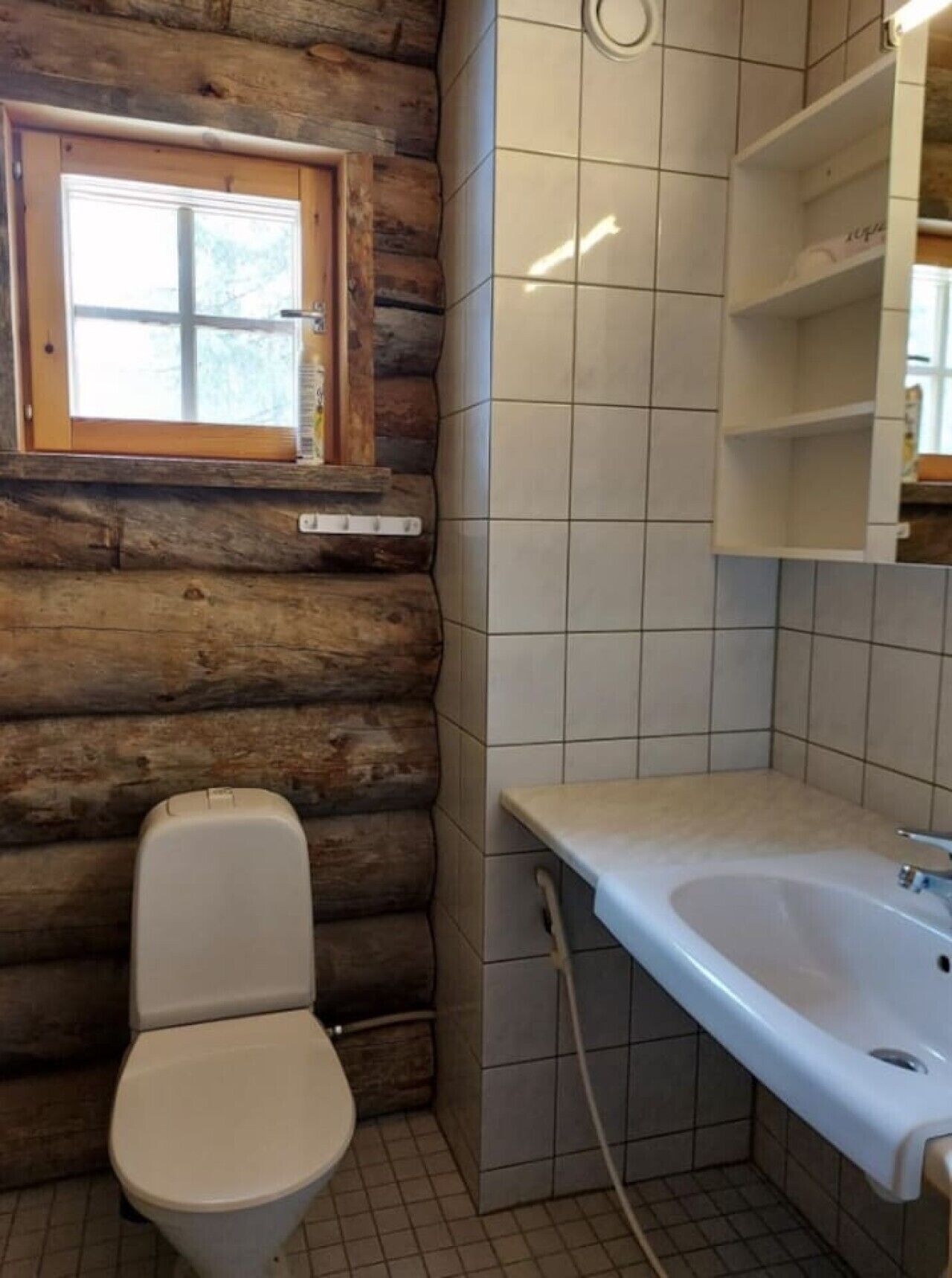 Un baño con inodoro, lavamanos y ventana.
