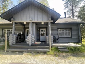 A log cabin with a porch, a bicycle, and a door with a window. - Mäntyruka A2 | Cozy 1BR Cabin | Sauna & Fireplace (Ruka)