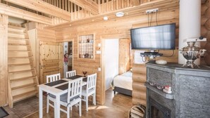 A wooden interior with a dining area, a television, and a fireplace. - Mäntyruka A2 | Cozy 1BR Cabin | Sauna & Fireplace (Ruka)