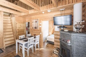 A wooden interior with a dining area, a television, and a fireplace. - Mäntyruka A2 | Cozy 1BR Cabin | Sauna & Fireplace (Ruka)
