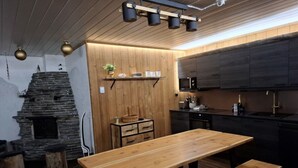 Et hyggeligt køkken med et træbord og bænk, en stenspir og moderne skabe.