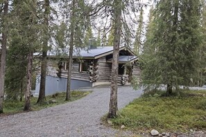 A log cabin with a gravel driveway leading to it, surrounded by trees. - Rukapirtti | Spacious 5BR Chalet with Sauna (Ruka)