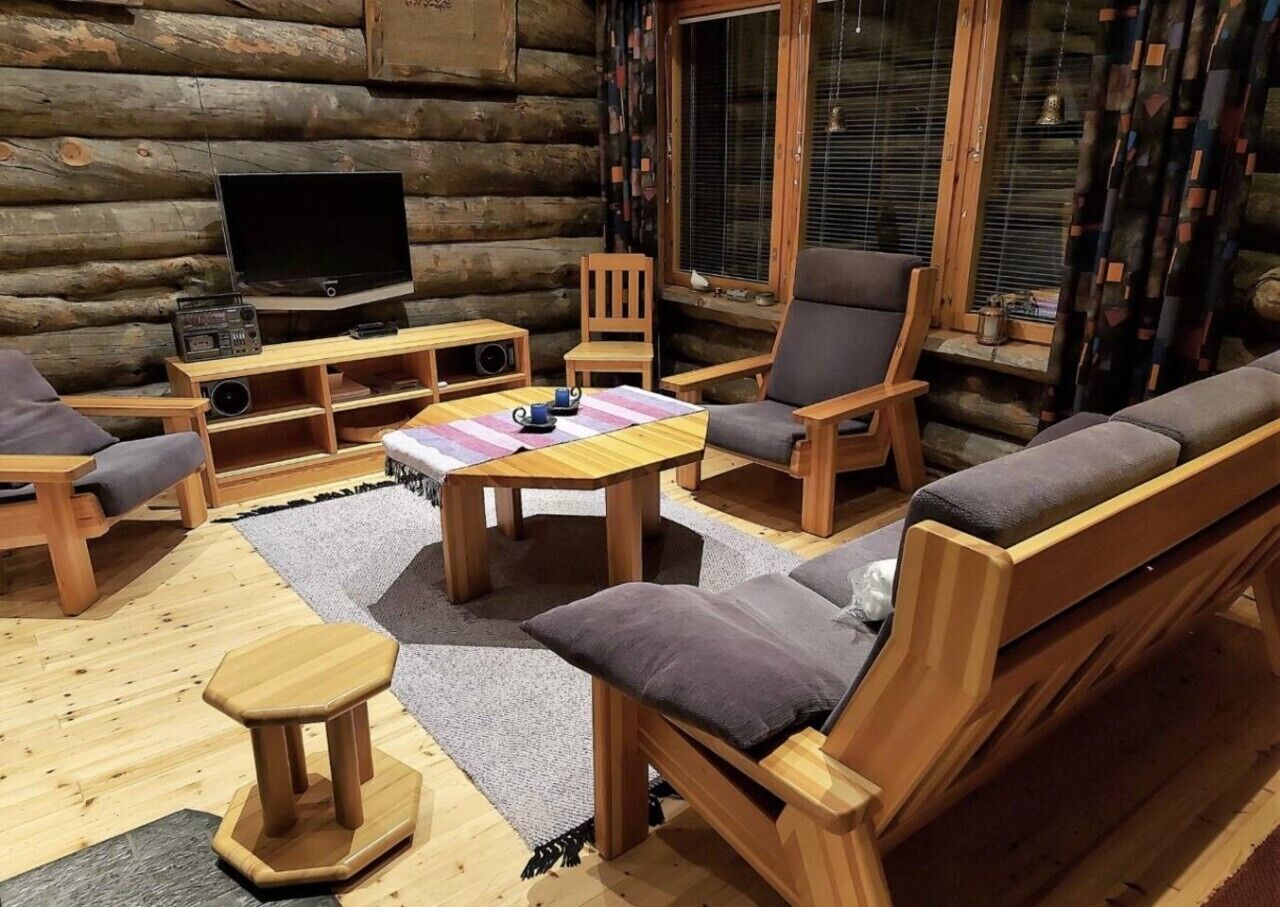 A log cabin interior with a sofa set, a television, and a radio.