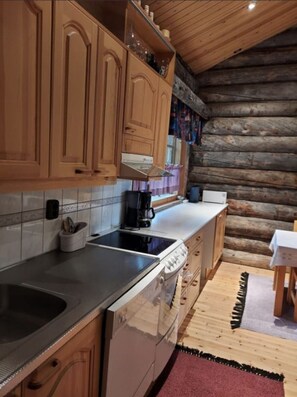 A kitchen with wooden cabinets, a stove, and a coffee maker. - Rukanjurmu 8 | Spacious 2BR Log Apt with Sauna (Ruka)