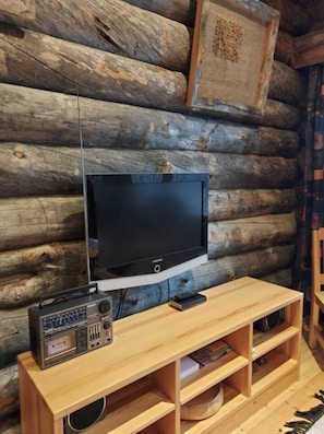 A television on a wooden stand with a remote control, a radio, and a smartphone. - Rukanjurmu 8 | Spacious 2BR Log Apt with Sauna (Ruka)